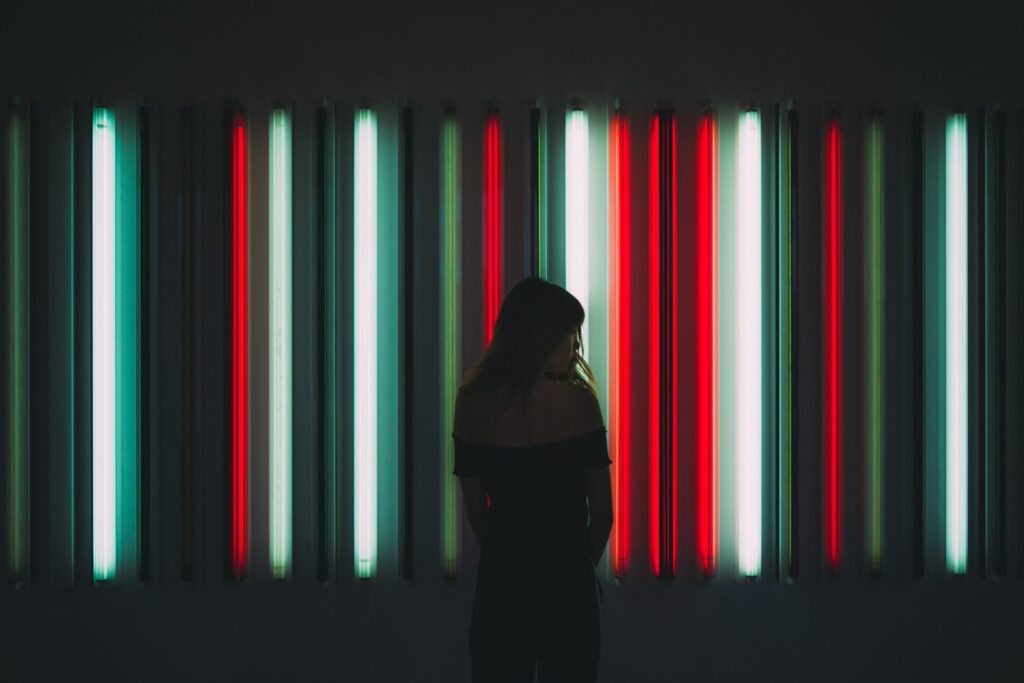 a woman standing in front of red and green fluorescent lights